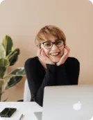 woman sitting down and smiling near computer