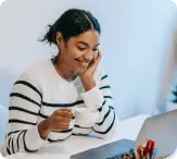 woman sitting down by computer with cup of tea
